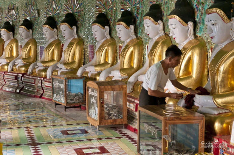 rows of buddhas lined up in gold painted wood