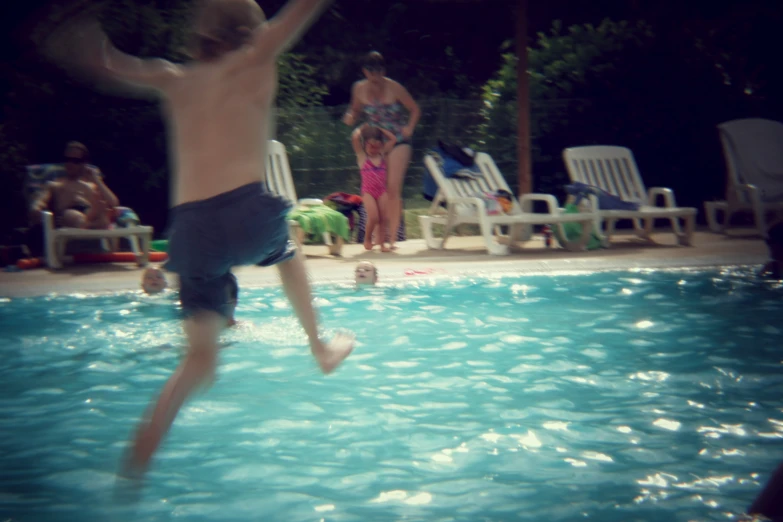 the child is jumping off of the pool into the water