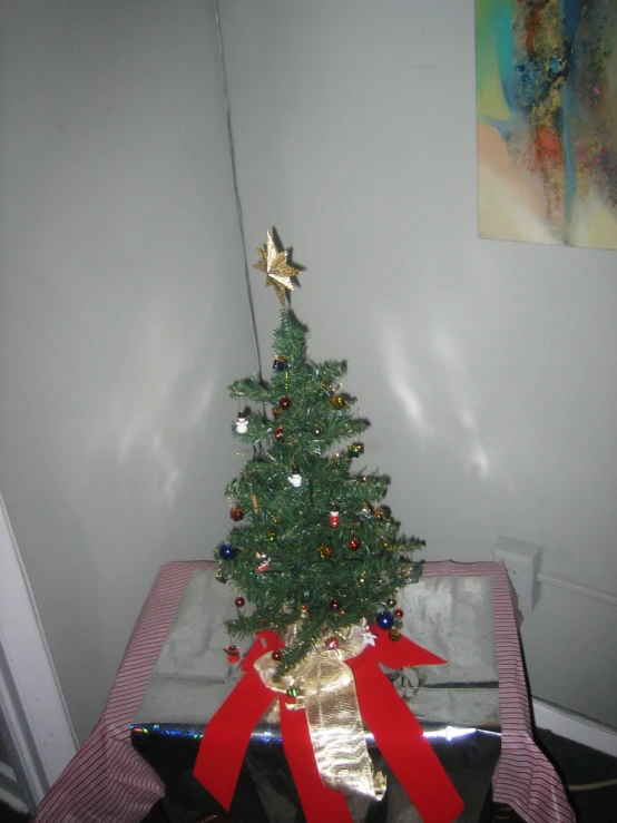 a small christmas tree with red ribbons on top of it