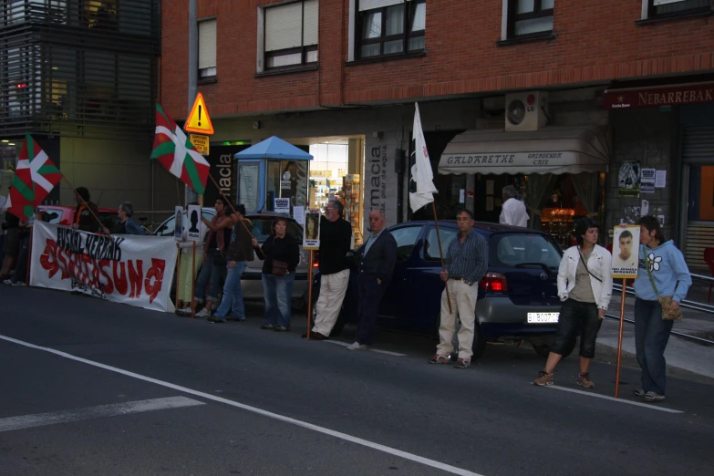 several people gathered around a car with a banner