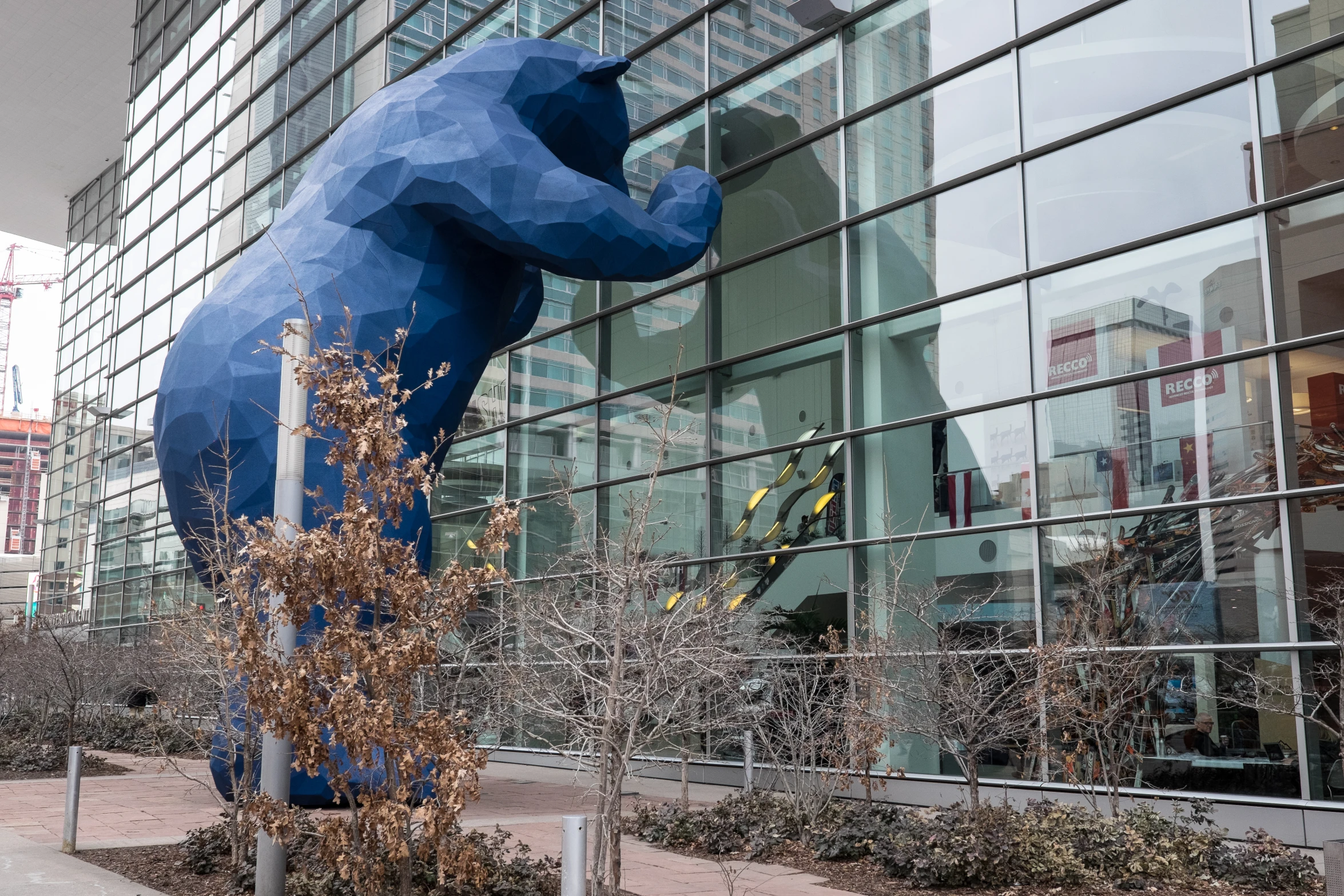a sculpture of a bear stands in front of a tall building