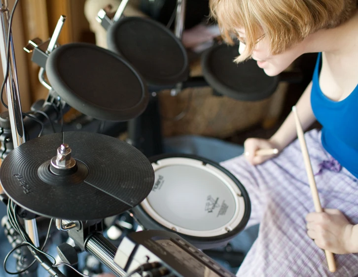 a woman in a blue shirt is playing on a drumset