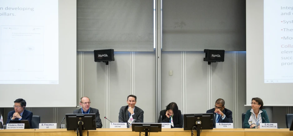 five people are talking during a meeting on a board