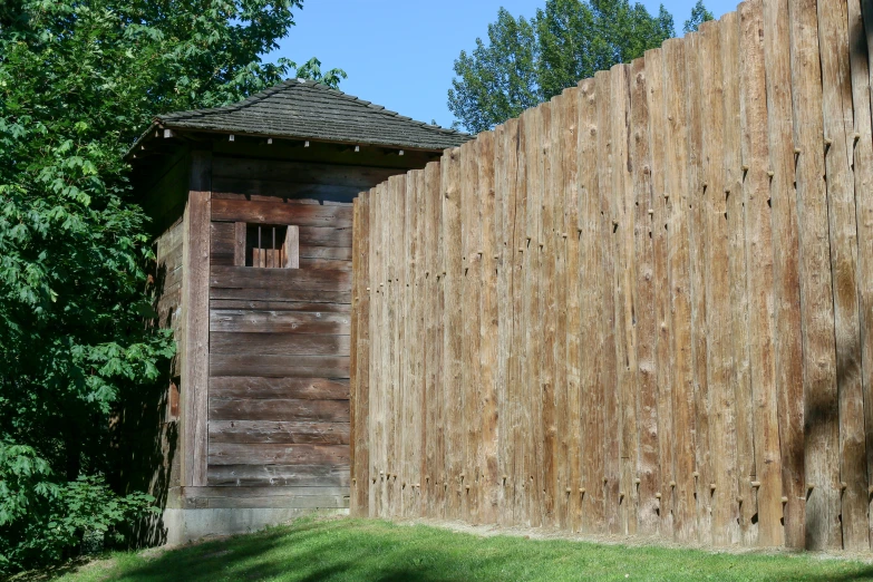 a tall wooden fence next to a building