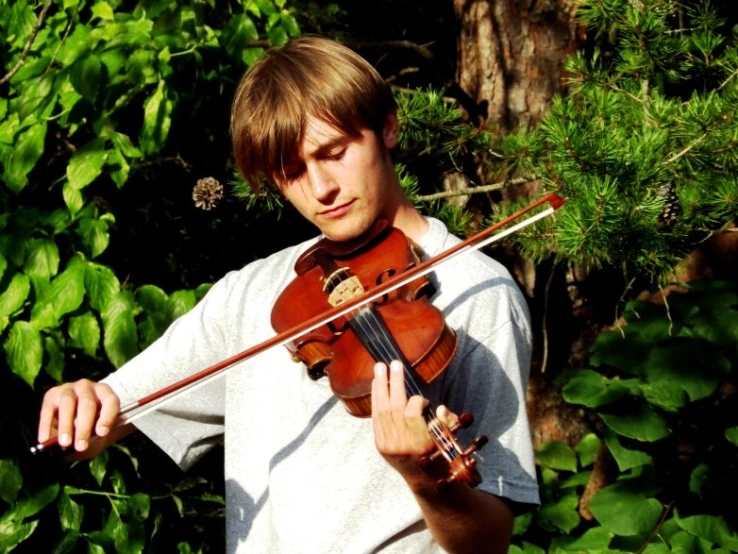 a man is holding his violin while playing in a wooded area