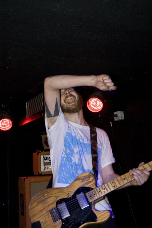 a man is holding his hand behind his head as he plays the guitar