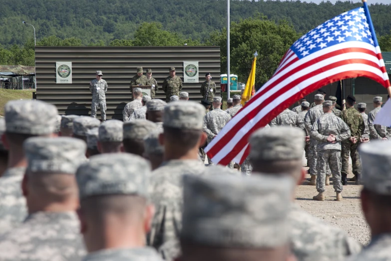 military men standing in a line holding an american flag