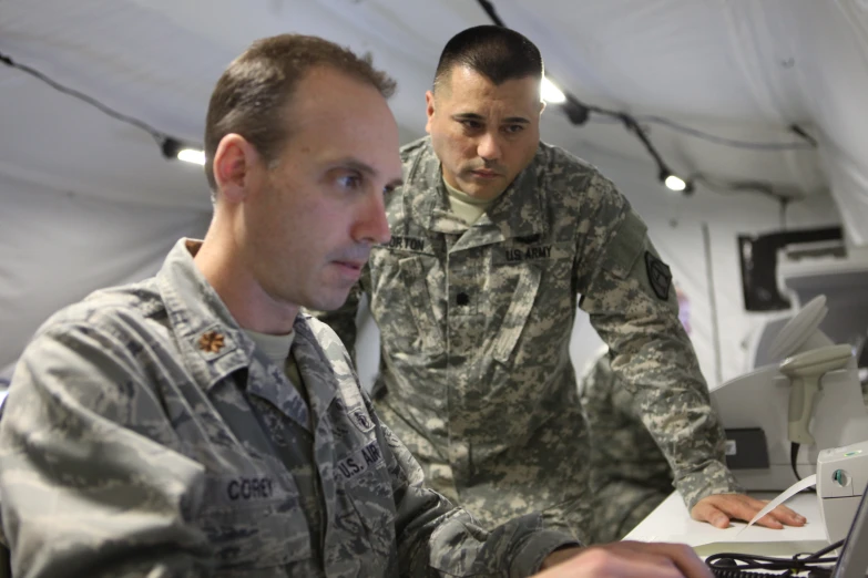 two military men are looking at a computer screen