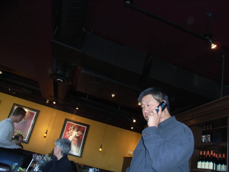 a man talking on his cell phone while standing in front of a bar