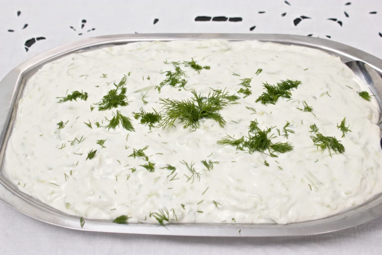 a silver tray of food with a lot of dill