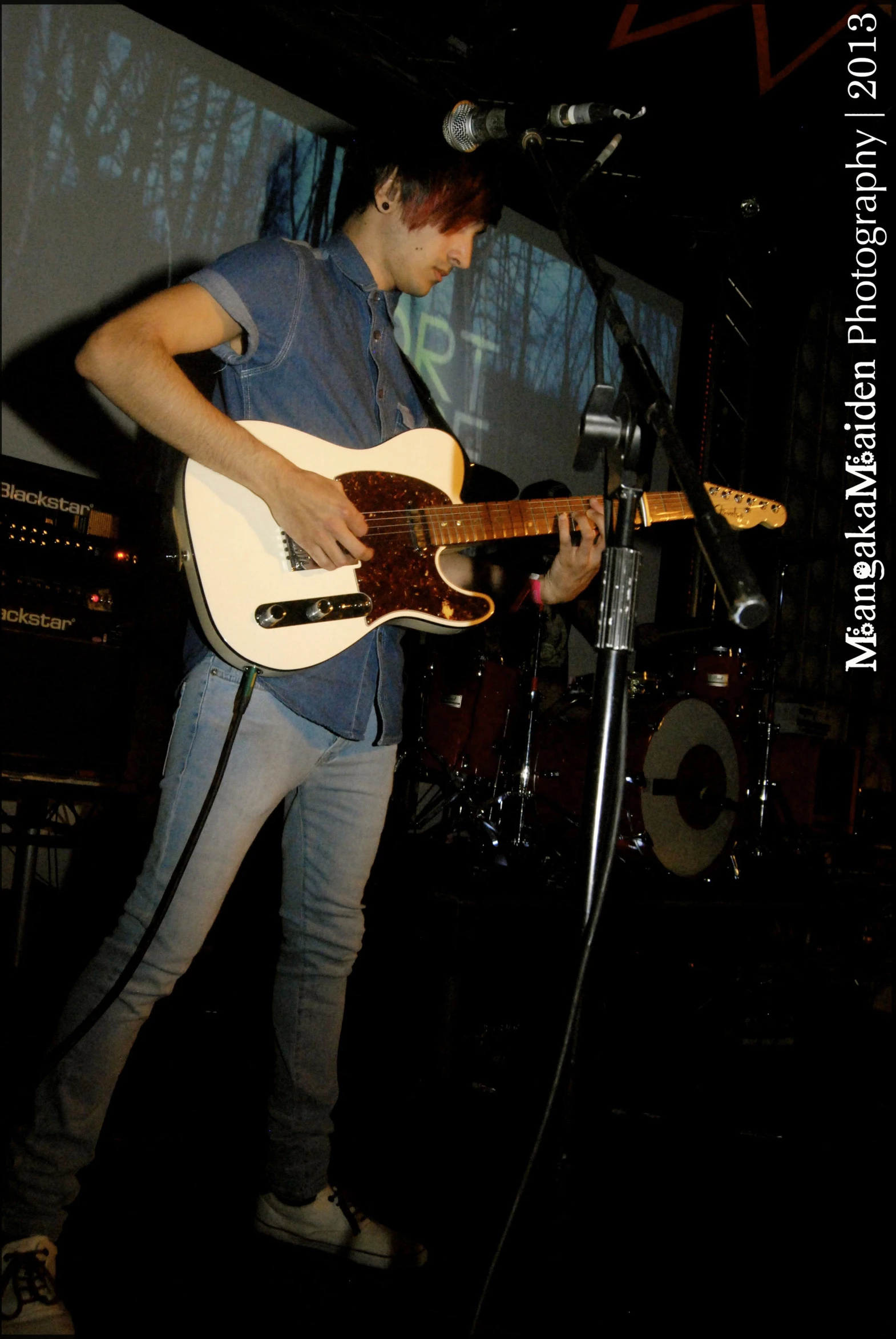 a man playing guitar while singing into a microphone