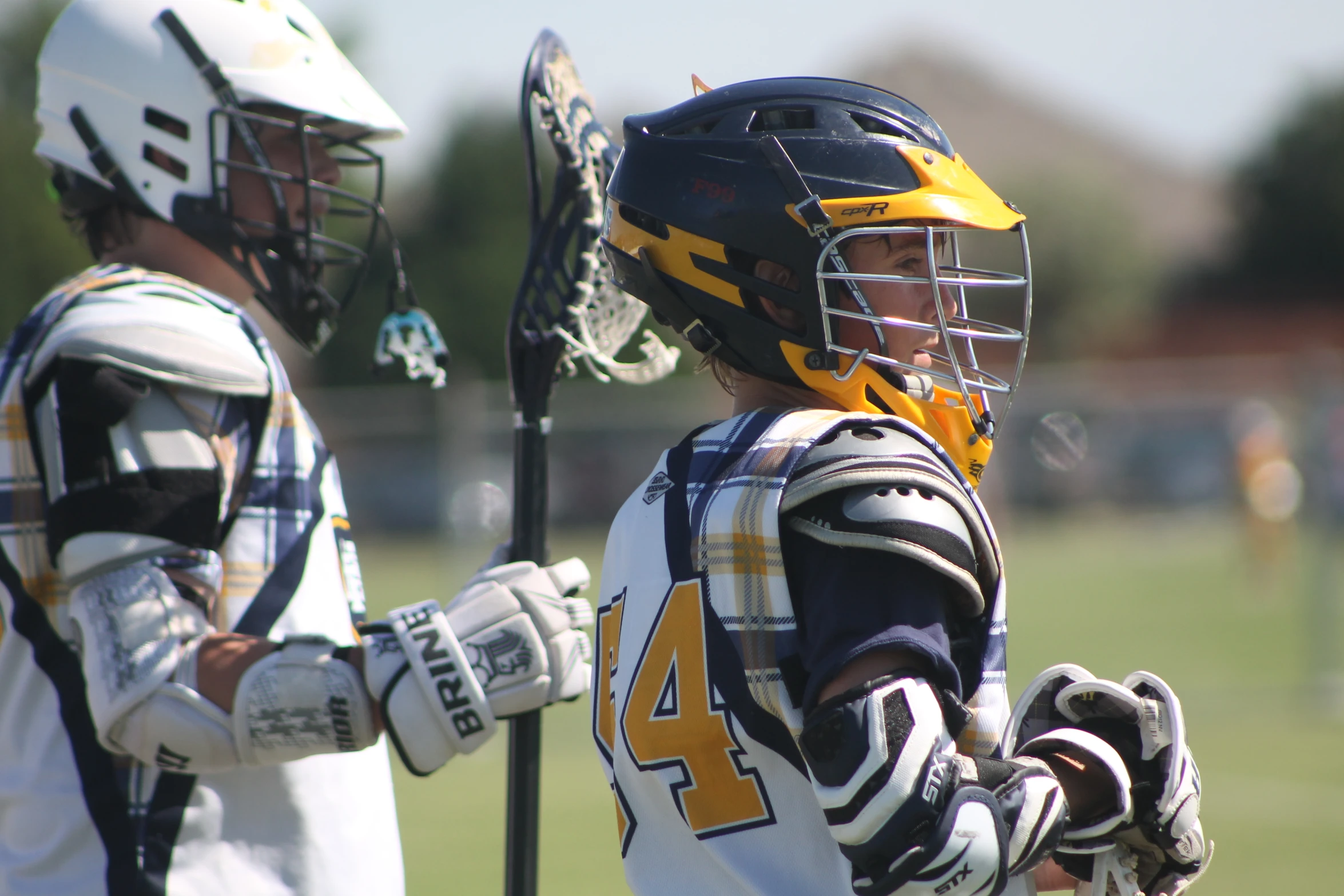 two s in helmets and lacrosse equipment are standing together