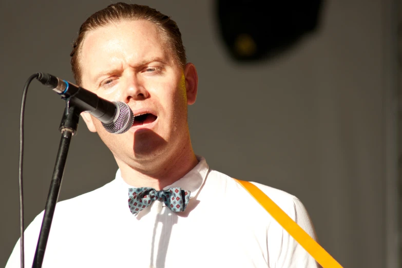 the man is singing into his microphone at an event