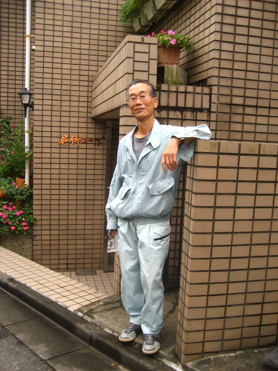 a man with a suit and glasses standing in front of brick building