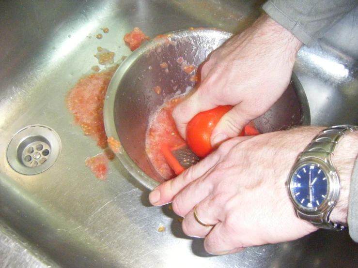 a man standing in front of a metal sink holding a carrot