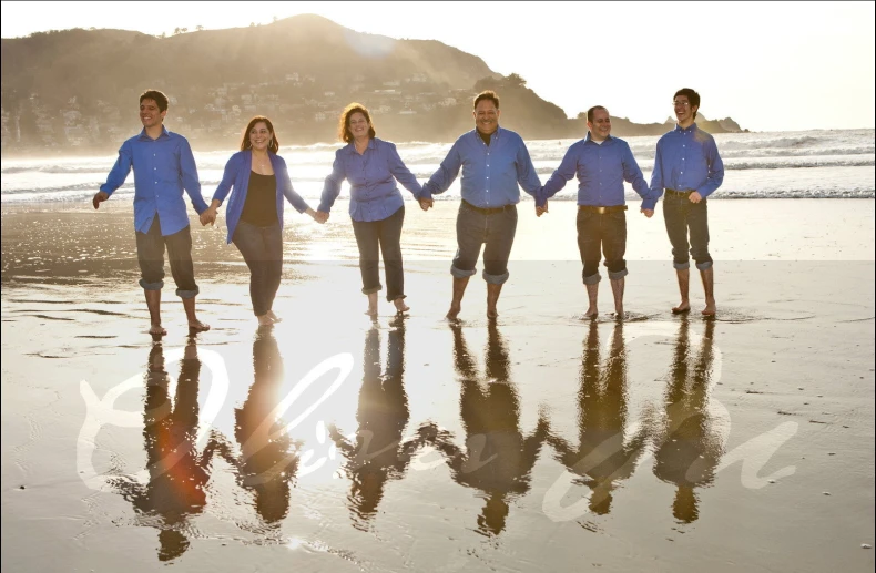 group of people with their hands together walking on the beach