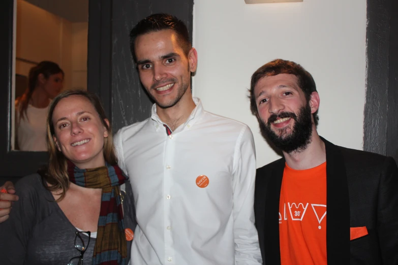 three people smiling for the camera in front of a door