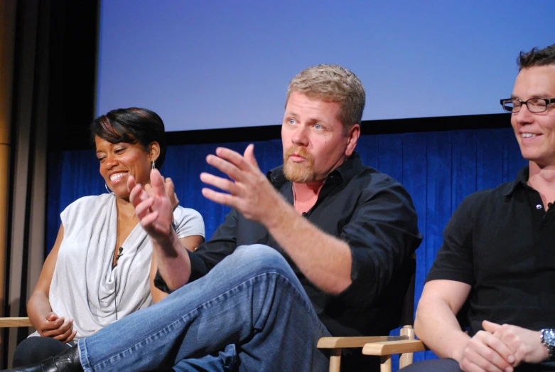 three actors sit together at an event and watch