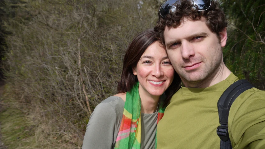 a woman poses with a man holding a camera