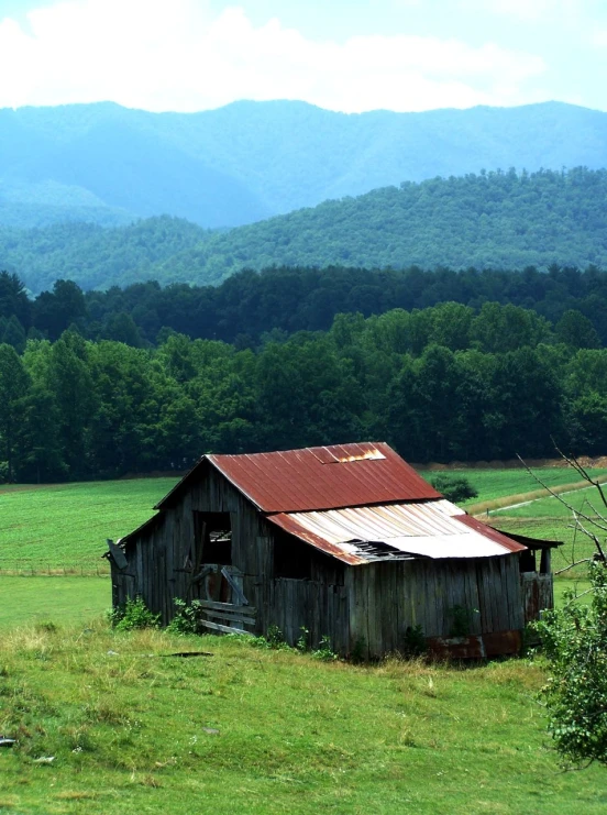 old barn in middle of a pasture with mountains in background