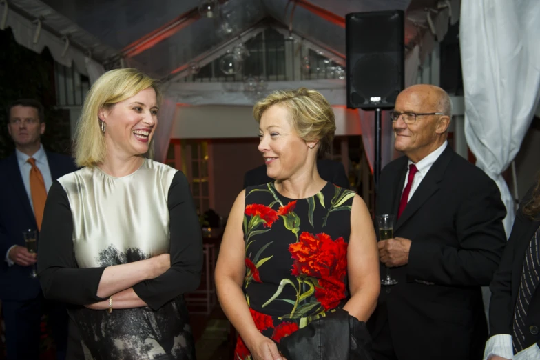 two ladies smiling and two men standing by