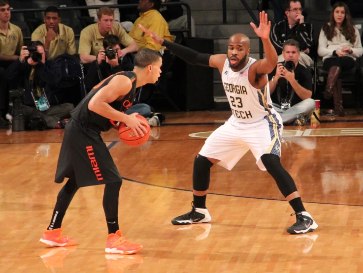 a man holds the ball in one hand and the other hand of another man holding a basketball in the other