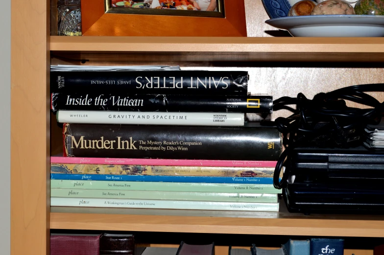 many books sit in a wooden bookcase on top of a television set