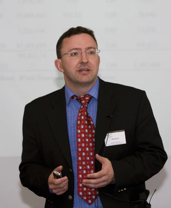 a man wearing a red and blue tie with black jacket