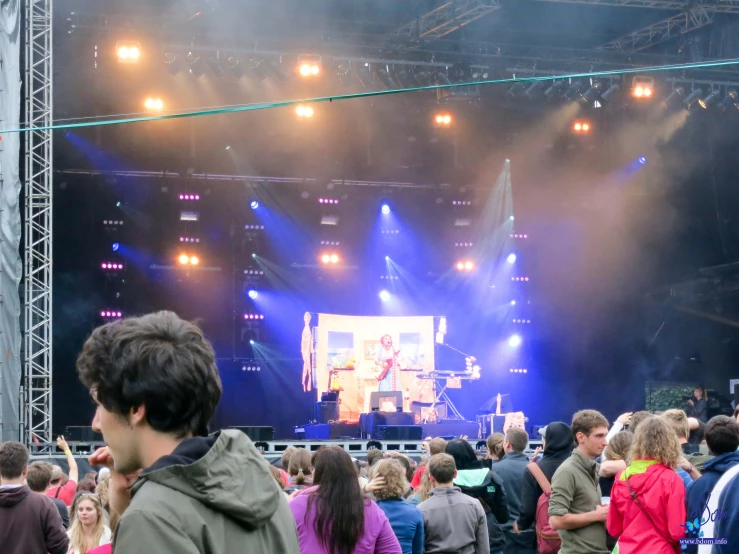 the concert stage at a festival is lit with purple lights