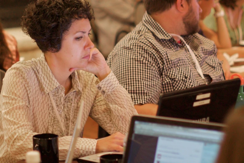 women are seated at a table and using laptops