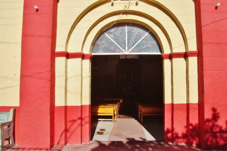 the large arched door of a yellow and red church