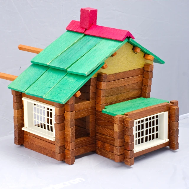 a wood doll house sitting next to a piece of wood