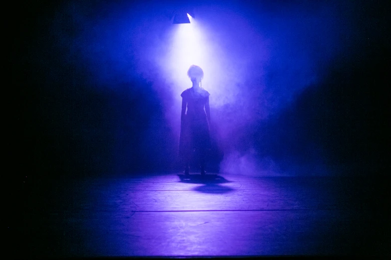 a woman standing alone on a stage at night