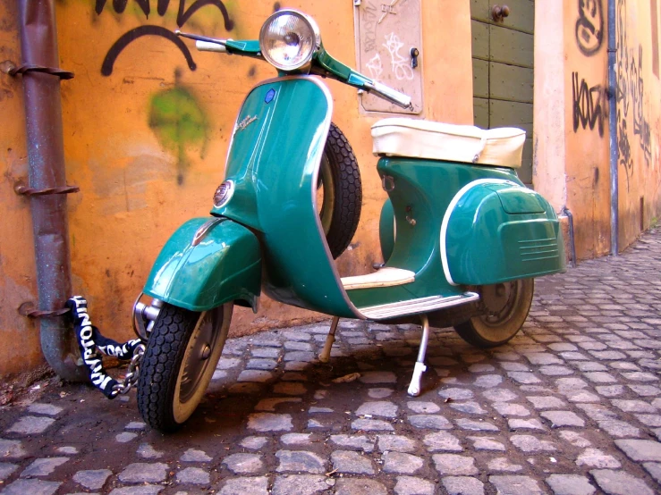 the moped is standing out by a wall and door