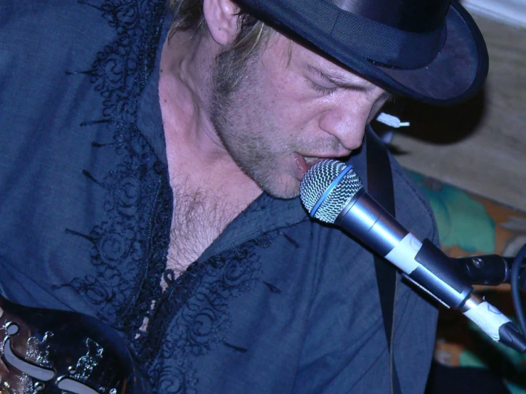 a man wearing a top hat while singing into a microphone