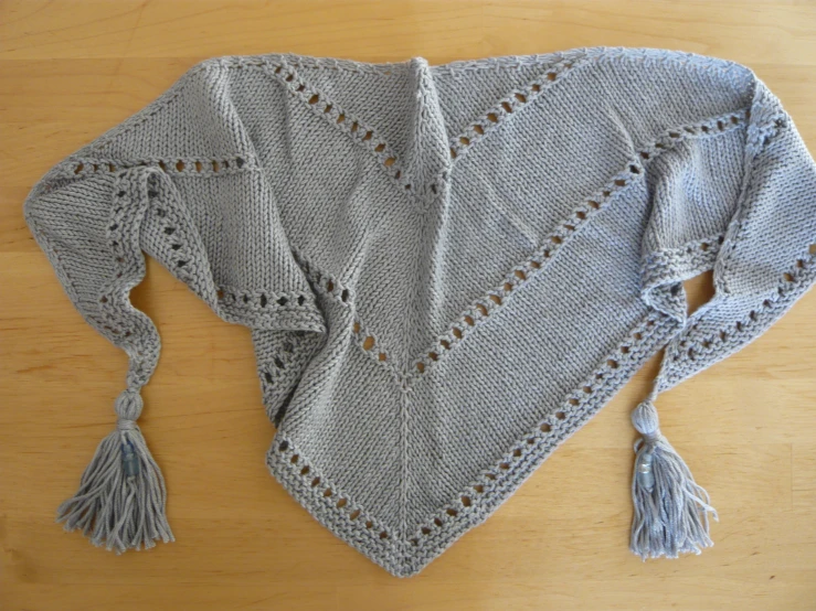 a grey sweater with crochet stitches and tassels