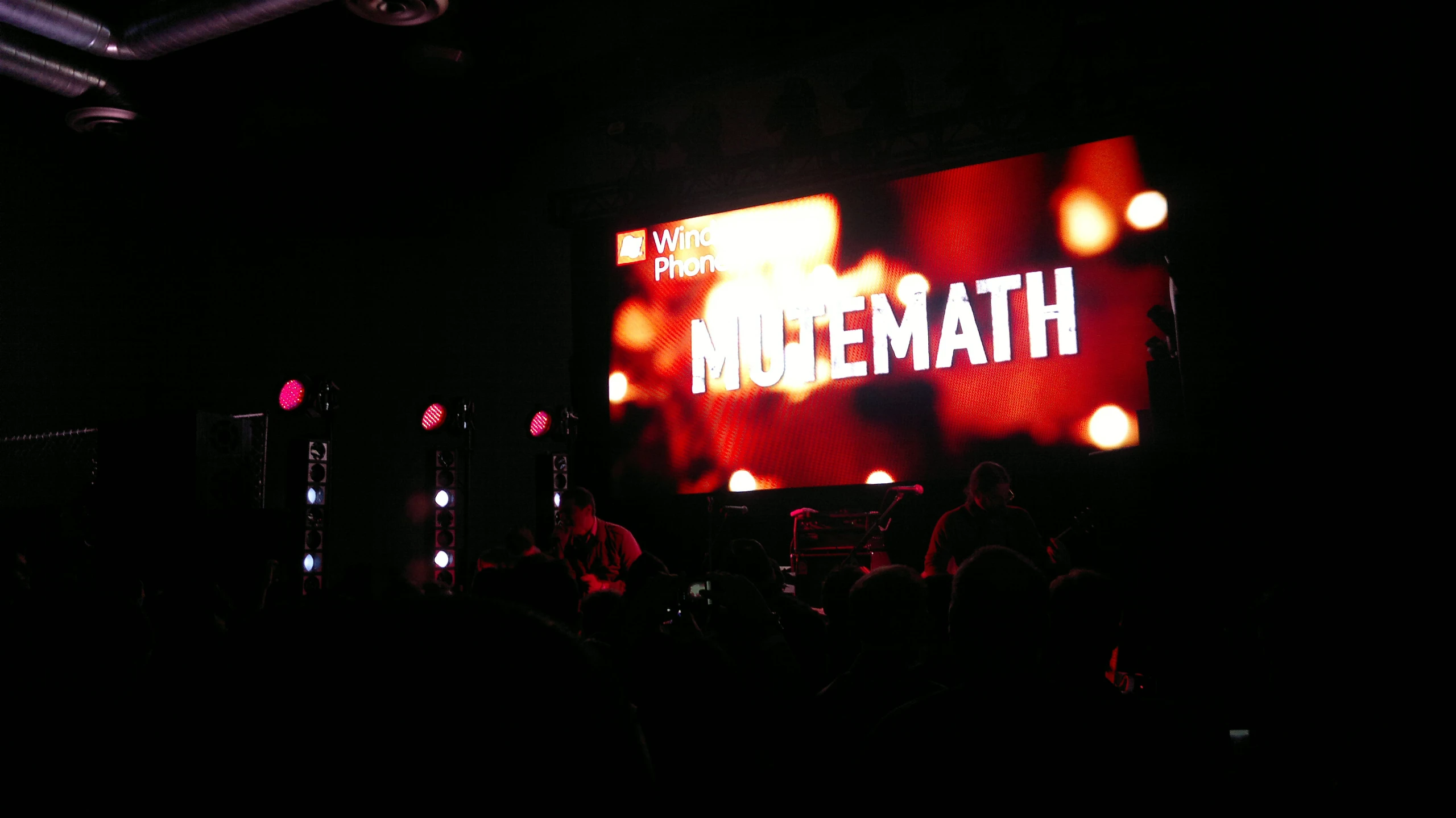 people standing on stage and watching a presentation on a large screen