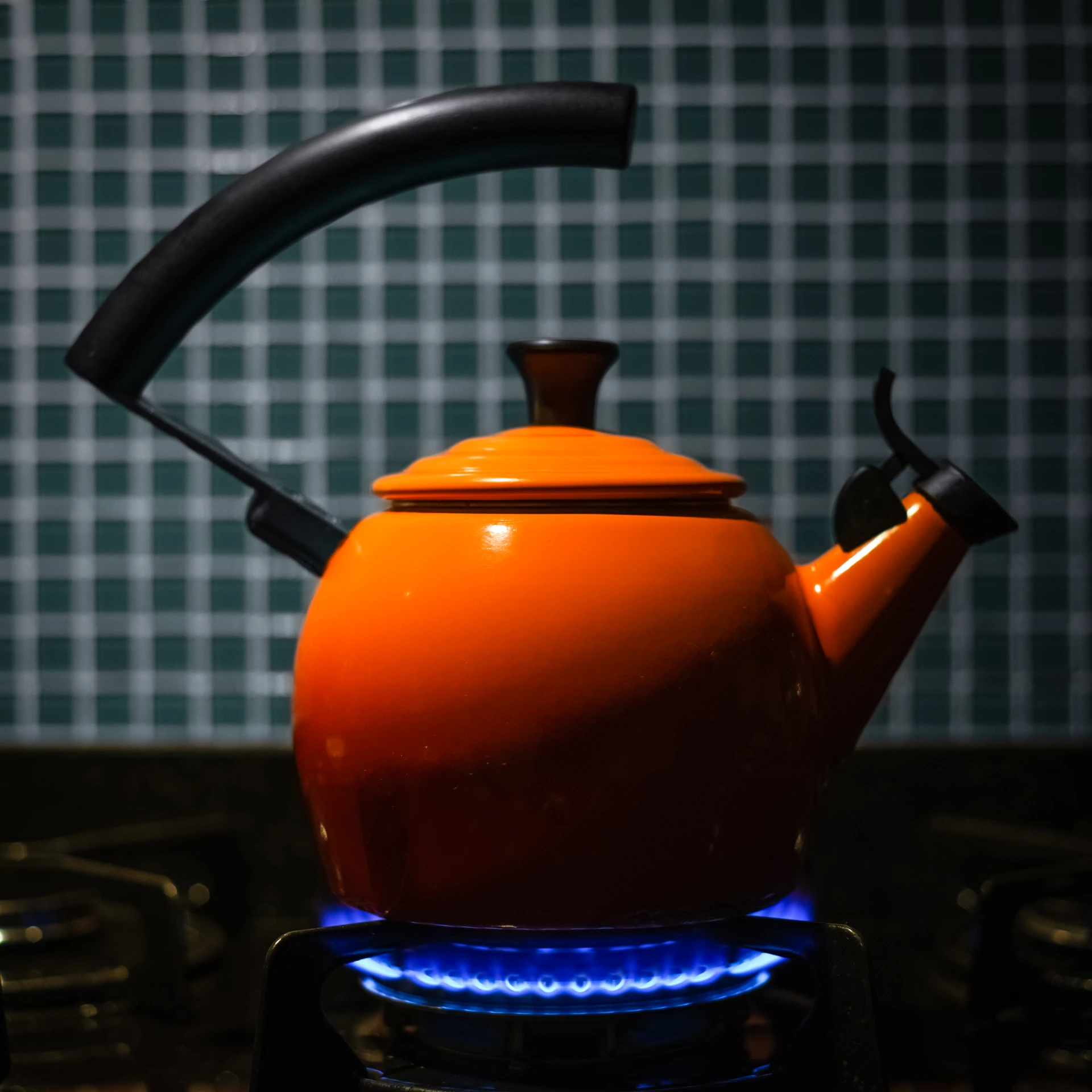 an orange teapot sitting on top of a stove