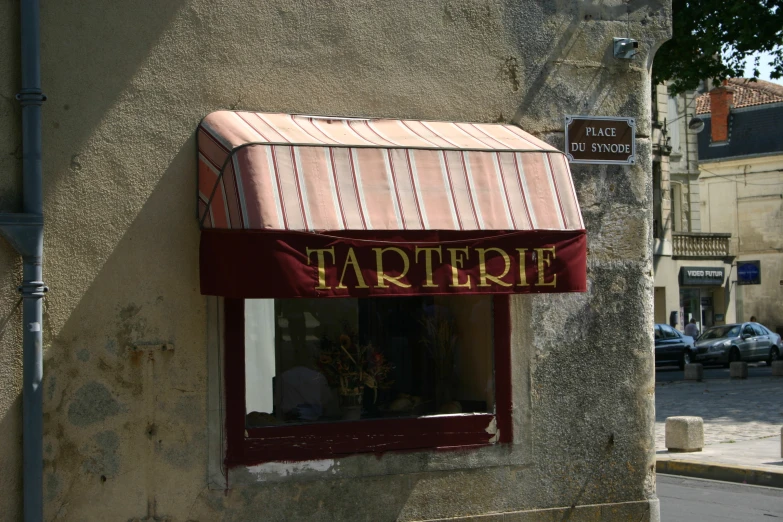 the storefront is painted beige with a maroon awning