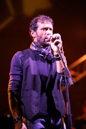 a male singer singing into a microphone while on stage