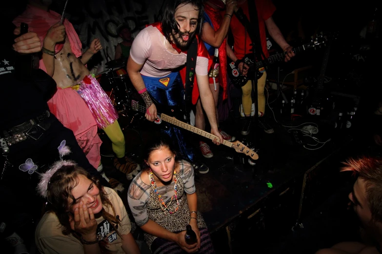 a girl is playing guitar near other people