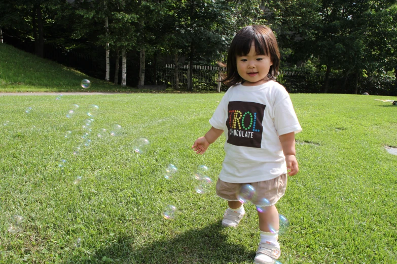 a small child walking on top of a lush green field