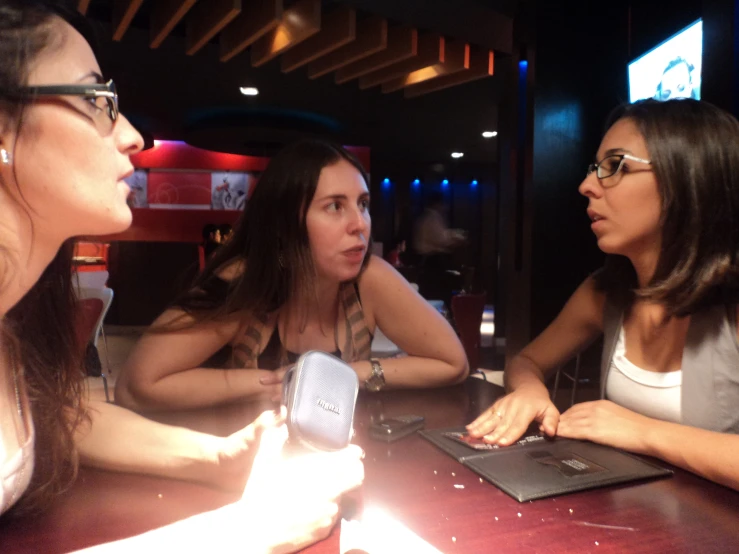 three young women are talking to each other in a bar