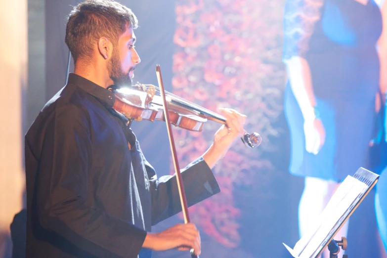 a man standing holding a violin with musical equipment