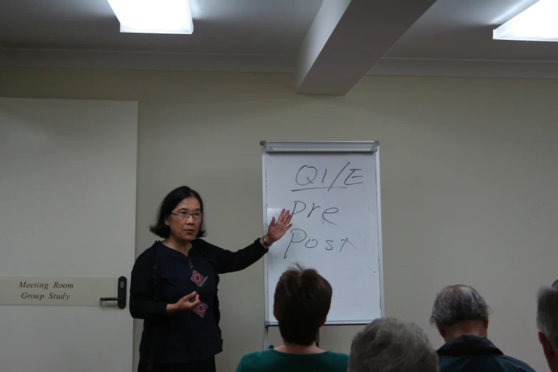 a lady standing in front of a group holding a white board