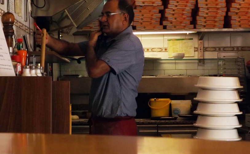 a man is talking on his cell phone in the kitchen