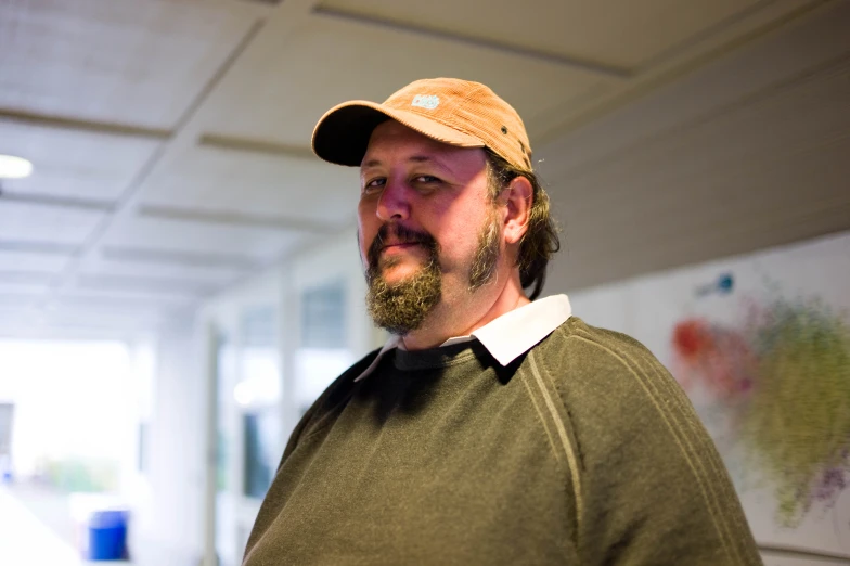 a man standing in a white room with a hat on