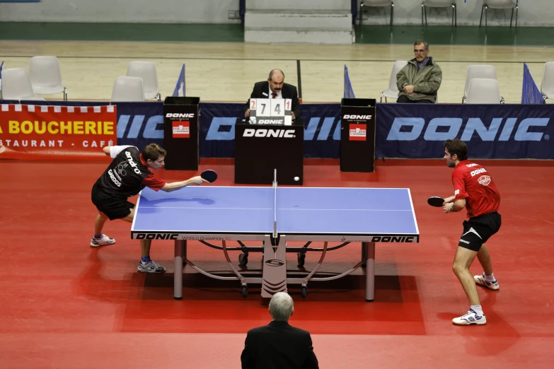 two players play table tennis as spectators look on