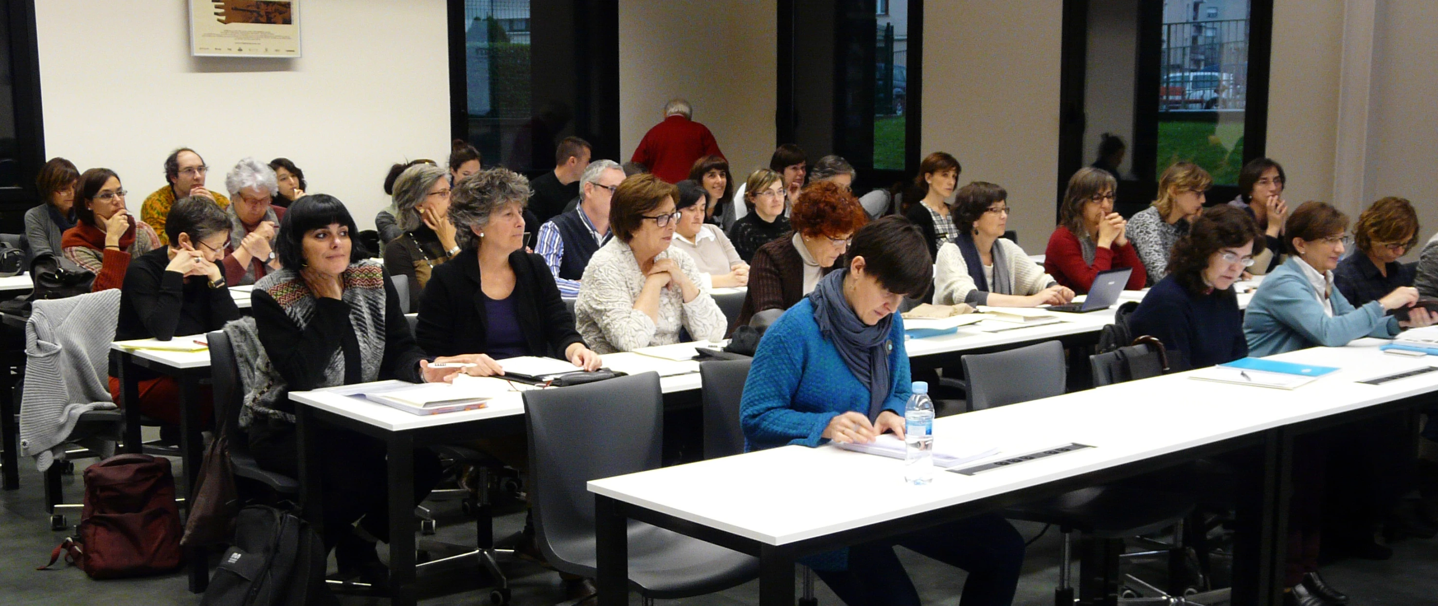 people sitting down in a room with white tables