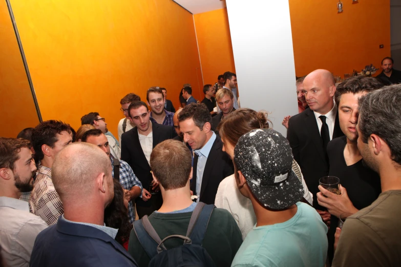 a large crowd in a narrow hallway with orange walls